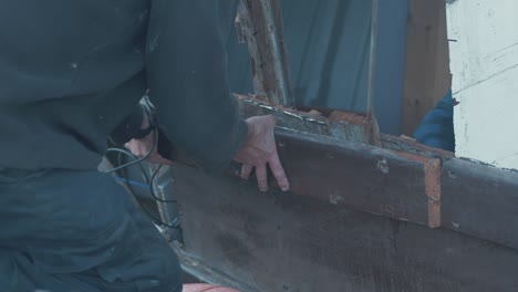 carpenter removes section of rubbing strake on eighty year old wooden boat