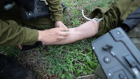 Injured-soldier-get-arm-IV-fluid-therapy-by-combat-medics,-close-up