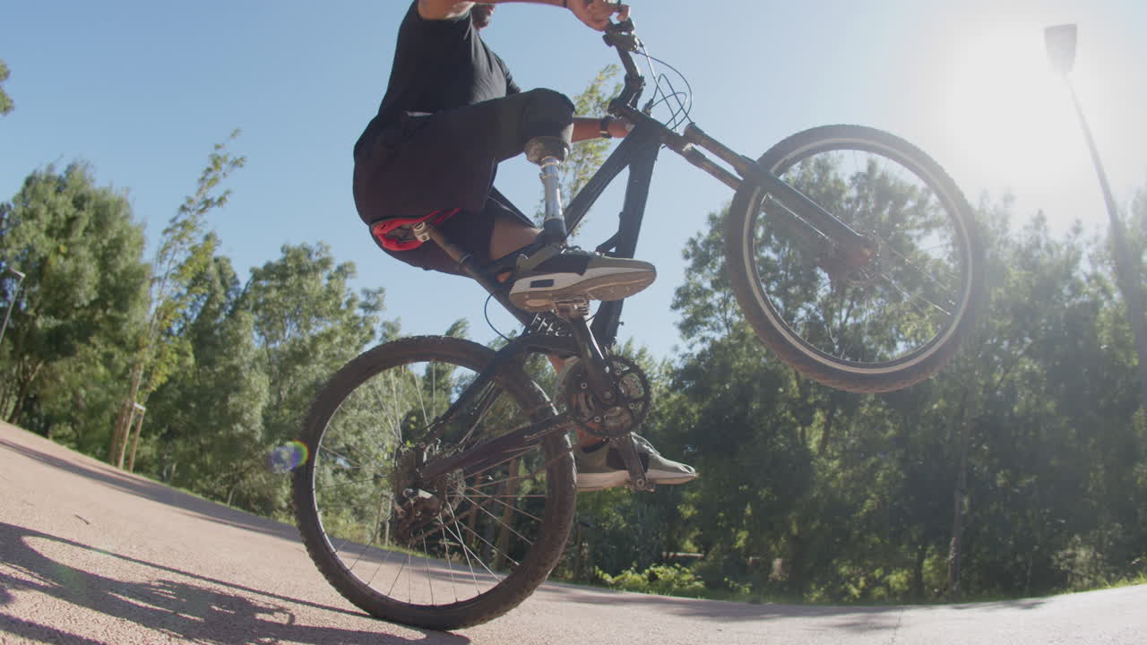 Campo lungo di uomo con disabilità che fa un trick in bici all'aperto