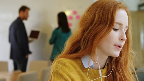 diseñadora gráfica escuchando música en auriculares en la oficina 4k