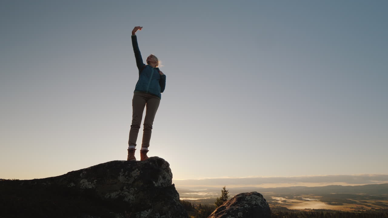 una mujer activa toma fotografías de sí misma en la cima de una alta montaña al amanecer se encuentra en la parte superior de la persona