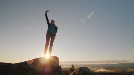 Una-Mujer-Activa-Toma-Fotos-De-Sí-Misma-En-La-Cima-De-Una-Alta-Montaña-Al-Amanecer,-Se-Encuentra-En-La-Parte-Superior