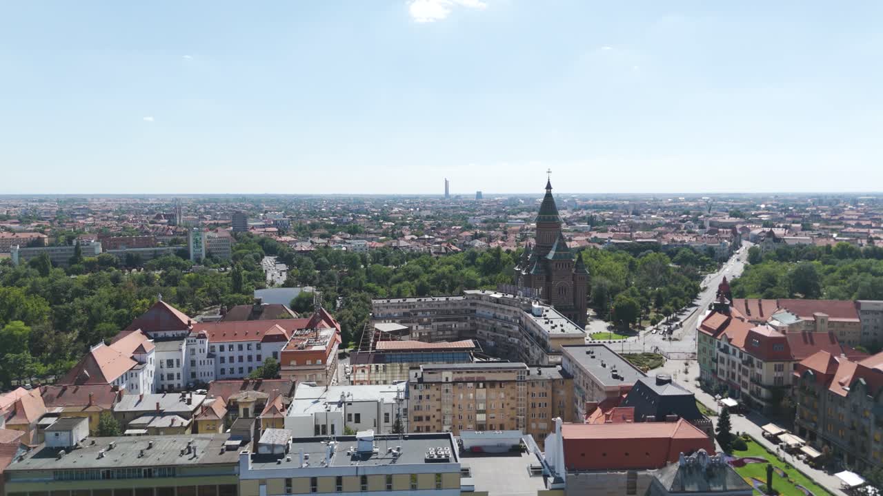 Scenic drone flyover of urban buildings in Timisoara leading to the Metropolitan Cathedral, showcasing cityscape and architectural landmarks