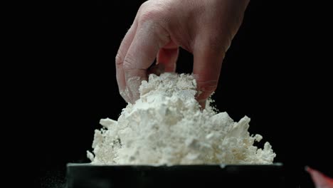 someone pulls a miniature skull from a pile of white powder and shakes the excess powder off