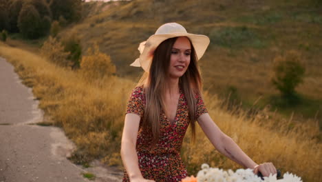 a girl in a dress riding a bike with flowers in a basket and laughing enjoying the freedom and summer air. slow motion.