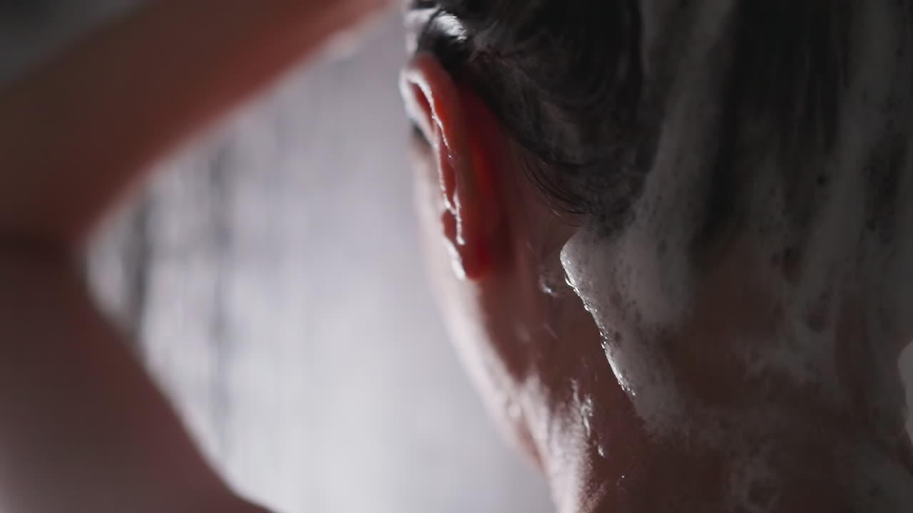 샤워 유에서 은 머리카락에 부드러운 거품을 가진 여성. 편안한 여자는 화장실에서 화장품 젤로 머리카락을 는 것을 즐긴다. 아름다움과 신체 관리 의식