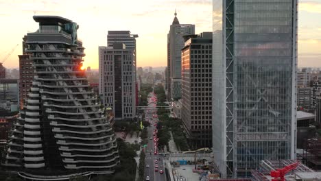 Cinematic-aerial-pull-out-shot,-drone-flying-above-Songgao-road-with-high-rise-skyscrapers-and-apartment-complex-alongside-at-sunset-in-downtown-Xinyi-district,-Taipei-city,-Taiwan