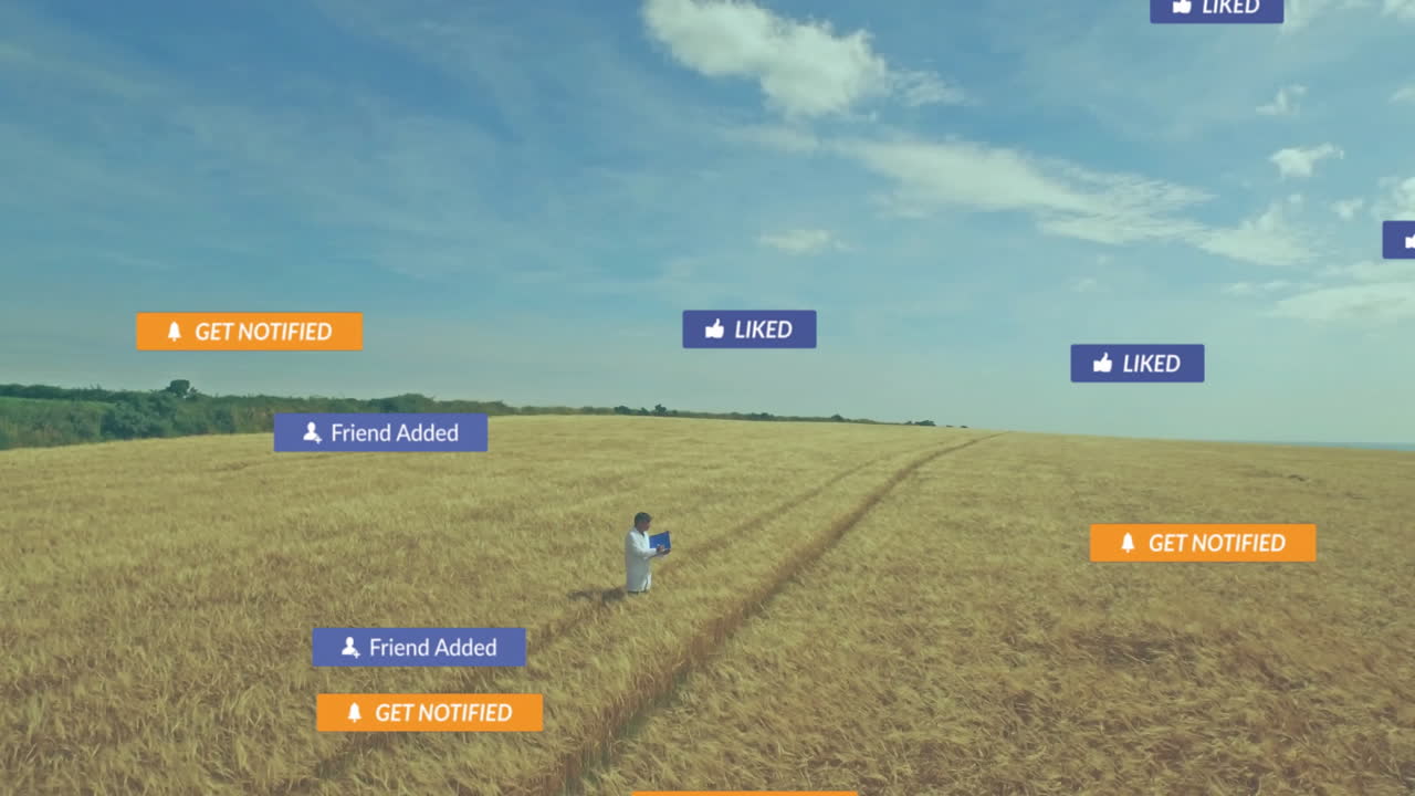 Agriculture researcher standing in wheat field, holding laptop with floating social notifications