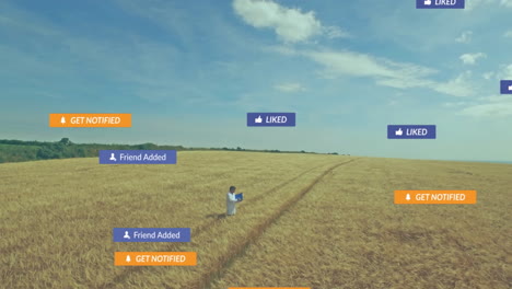 agriculture researcher standing in wheat field, holding laptop with floating social notifications