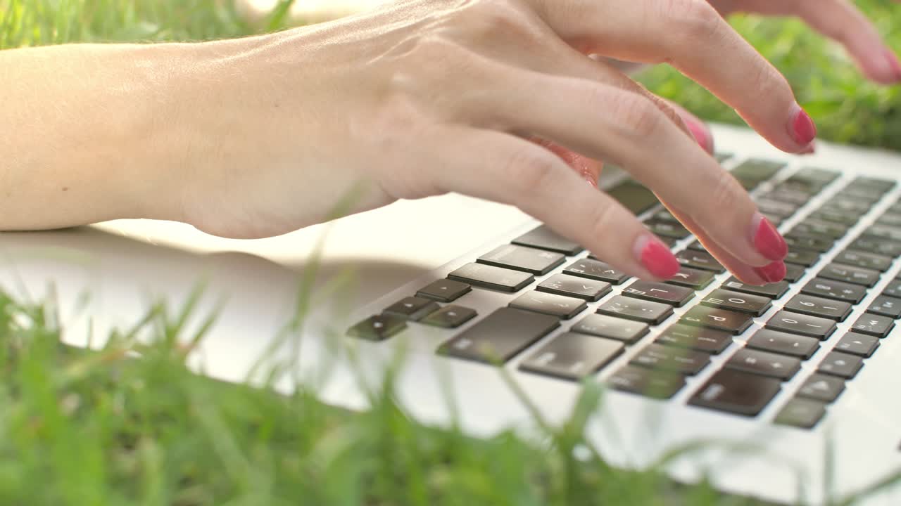 Young woman typing on laptop keyboard at nature.