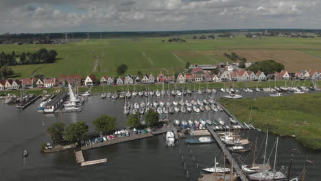 aerial backing up showing the marine port area for pleasure boats and sailboats with typical houses of the dutch village of durgerdam at the durgerdammerdijk near amsterdam on an overcast day