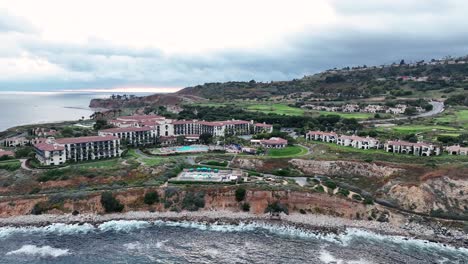 aerial tracking shot of migratory birds flying along coastline with view of terranea resort hotel in rancho palos verdes