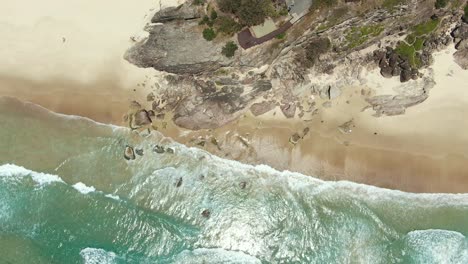 rocky headland ,crystal clear water, small waves, from the vertical , drone shot holding still for wonderful footage