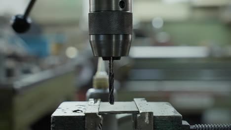 close up of worker using drill press on metal in workshop