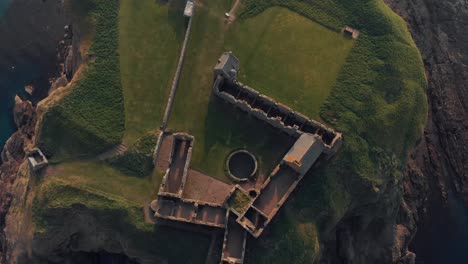 Medieval-fortress-Dunnottar-Castle-in-sunset,-ruined-medieval-cliff-top-fortress-dating-to-the-fourteenth-century