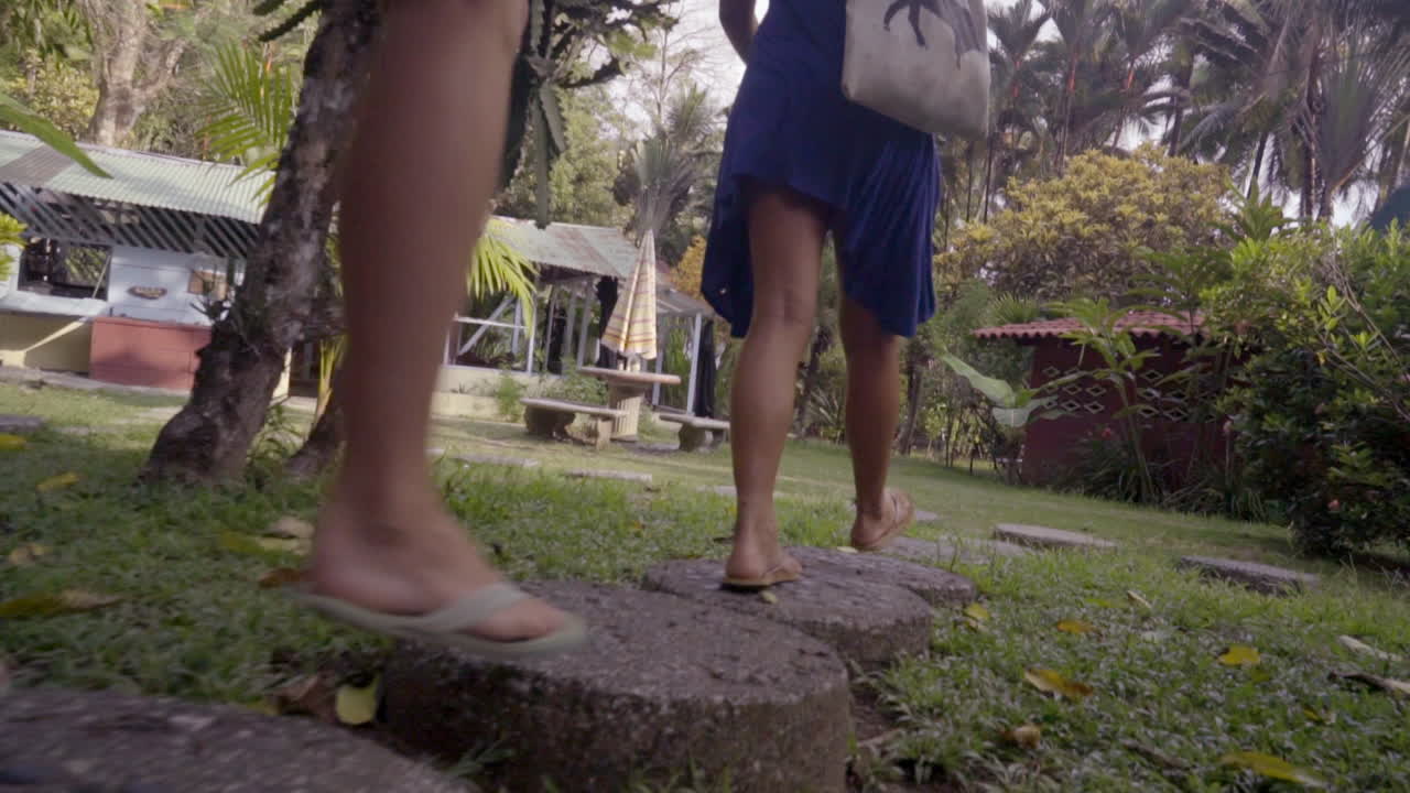 Two women enjoying their vacation and walking through the resort garden on stepping stones to the beach in Punta Banco, Costa Rica.