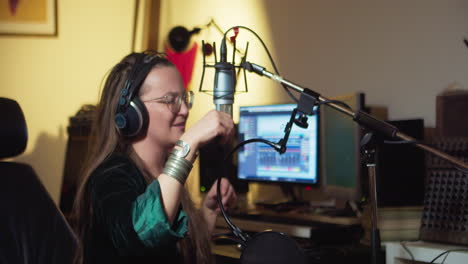 woman with headphones and a microphone, singing and very expressively experiencing her part