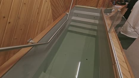 people gather at baptismal pool with steps into it during a sermony for a spiritual renewing with family and friends for a young adult with a seperation of plexiglass and railing to help participants