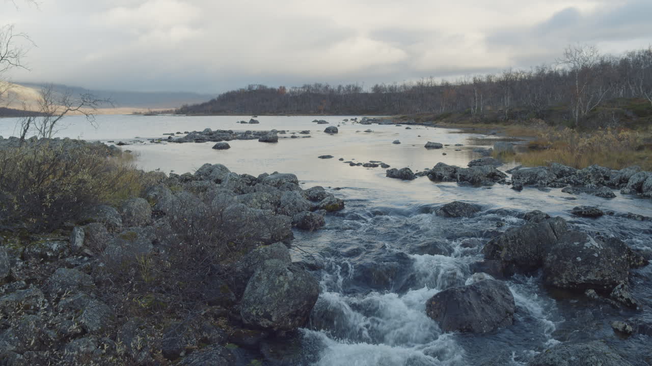 el agua fluye entre las rocas con el lago en la procedencia