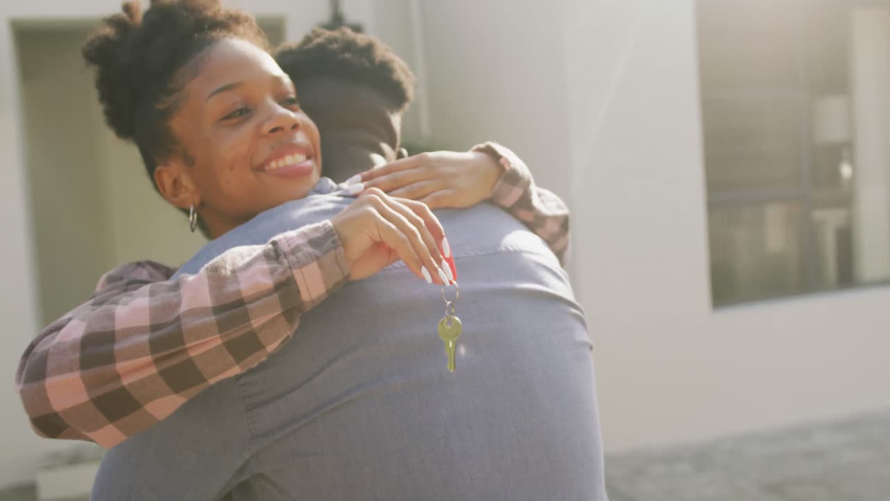 video de una feliz pareja afroamericana abrazándose y mostrando las llaves de una nueva casa