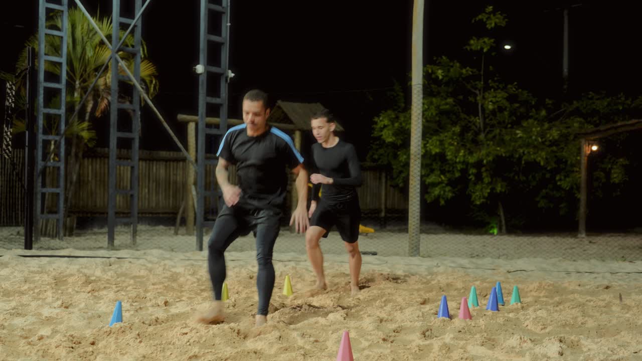 Two Men Training and Performing Agility Drills on Sand at Night