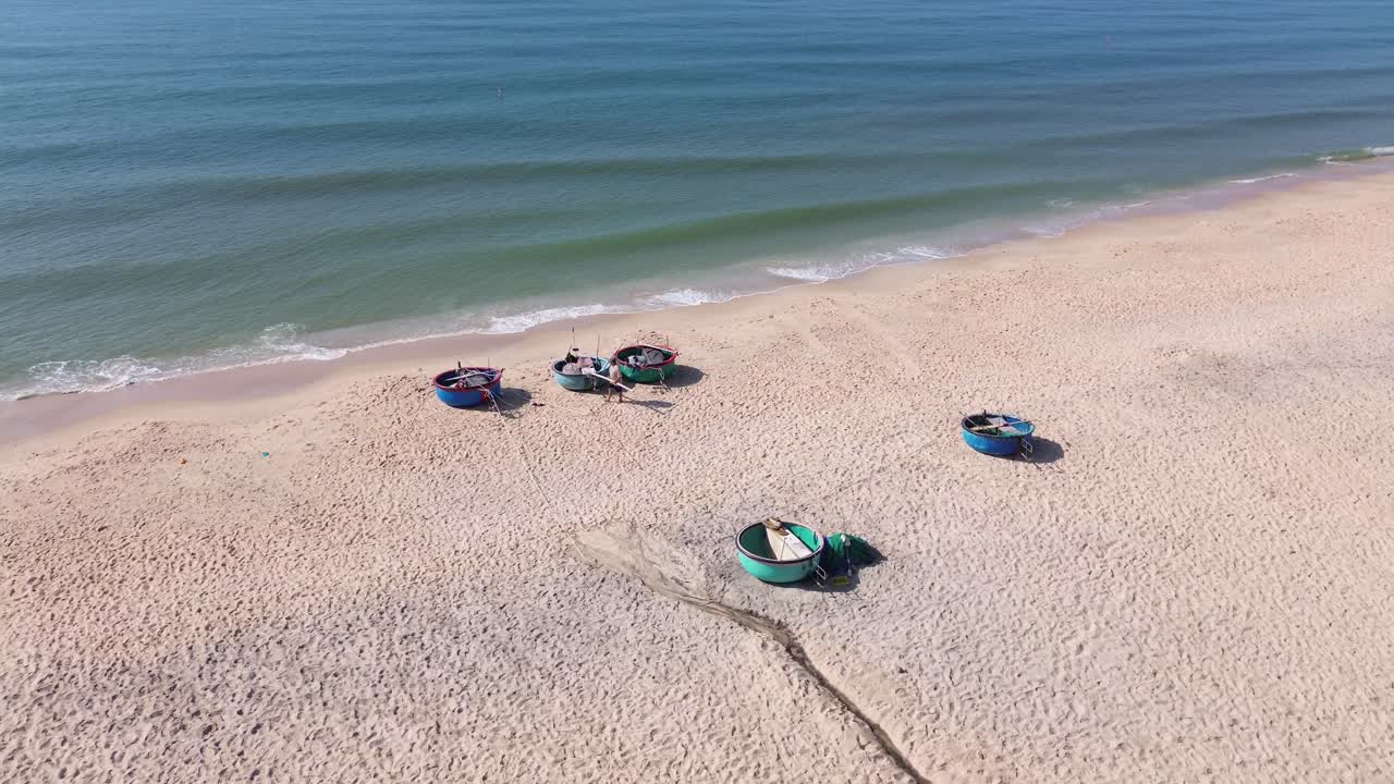 Drone flies half-circle from right to left over Mui Ne beach, keeping buckets and people walking in center, revealing resorts, white sand shore, and sea horizon.