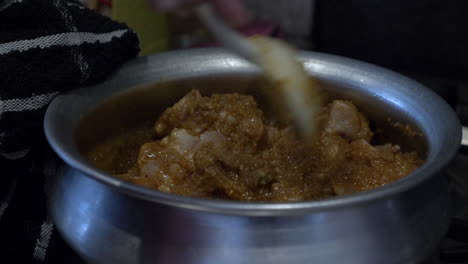 trozos de pollo marinados revueltos en una olla de acero