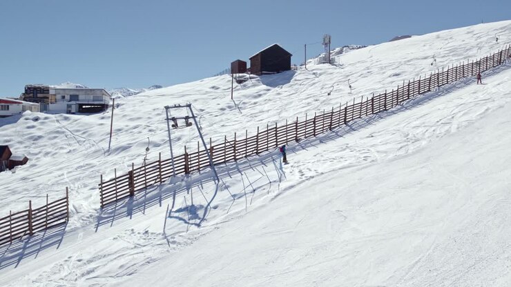 Aerial tracking shot of a skier using a ski lift to reach the top of the Farellones slope