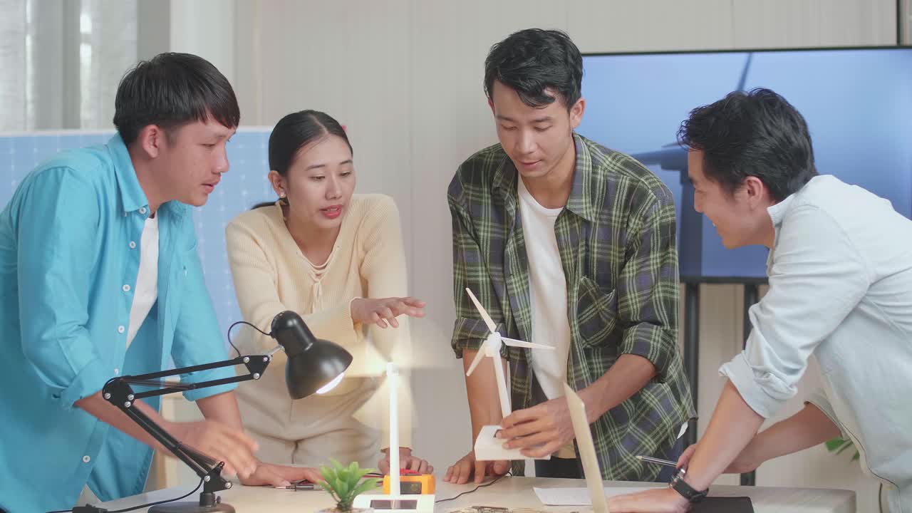 엔지니어링 그룹의 아시아인 남녀가 사무실에서 풍력 터빈을 테스트하는 동안 논쟁하고 있습니다.