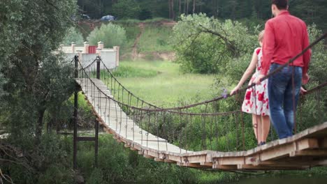 couple walking across a suspension bridge in nature