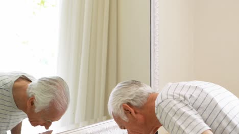 Hombre-Mayor-Cepillándose-Los-Dientes-Con-Cepillo-De-Dientes-En-El-Baño.