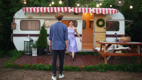 Lovely-Couple-Having-Fun-Near-Trailer-In-The-Park,-Slender-Girl-Jumping-Into-Arms-Ofher-Boyfriend-And-Spinning-Her-Around