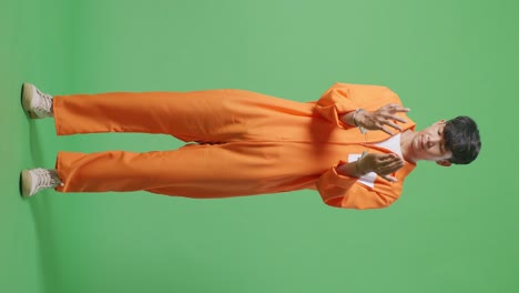 full body of asian male prisoner standing on the green screen background, looking at handcuffs and shaking his head being upset on what he did