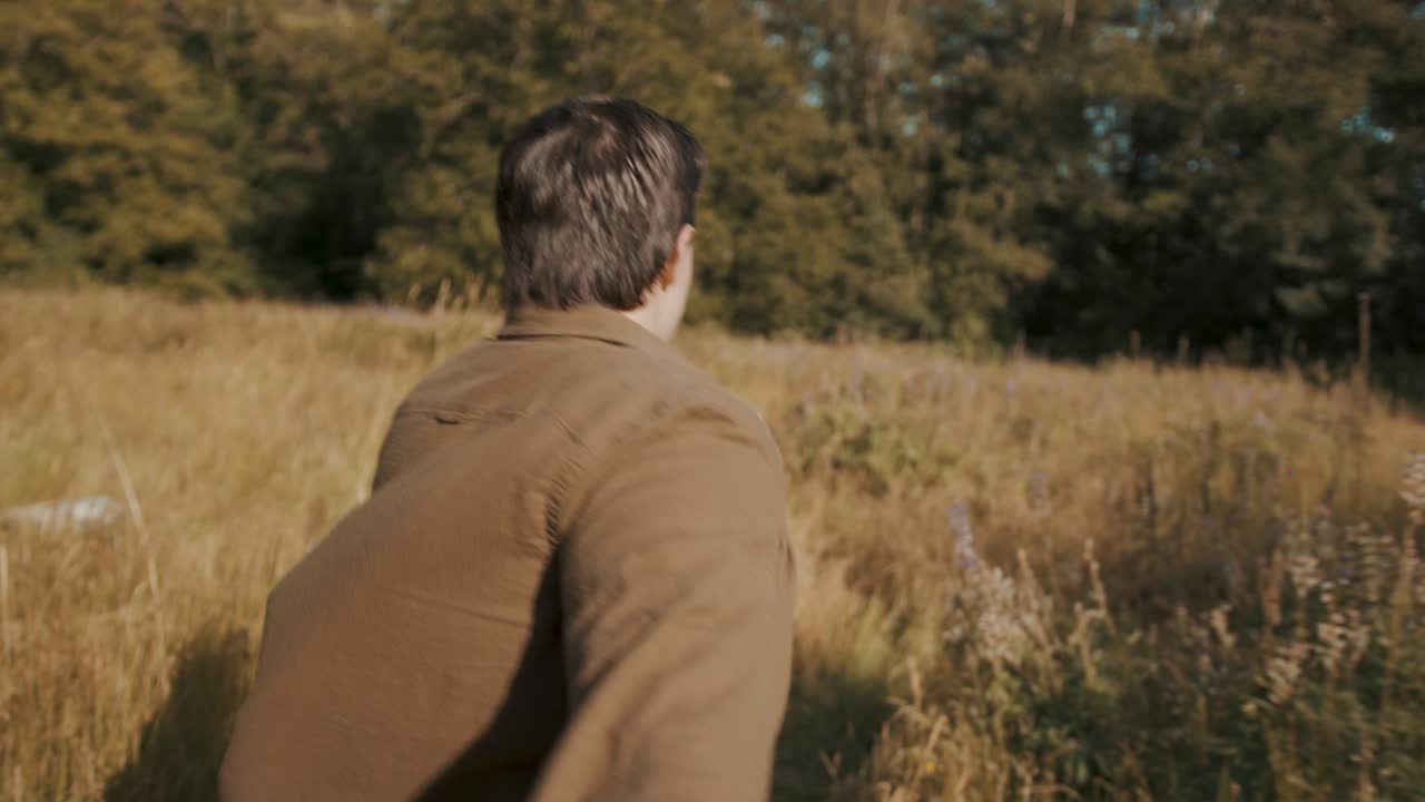 pov: 젊은 남자가 누군가의 손을 잡고 키 큰 잔디밭을 통해 그들을 이끌고 달리고 있습니다.