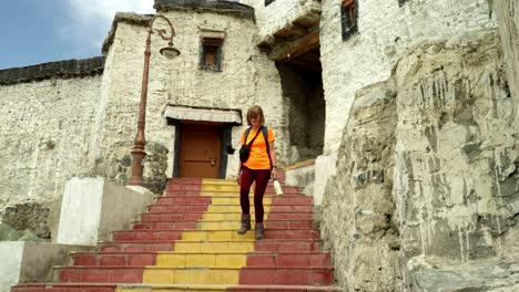 A traveler descends stairs at Thiksey Gompa in Leh, Ladakh, a serene Buddhist temple in the Himalayas. Older female tourist in hiking gear on adventure holiday of self discovery