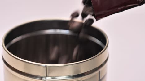 filling a metal container with roasted coffee beans