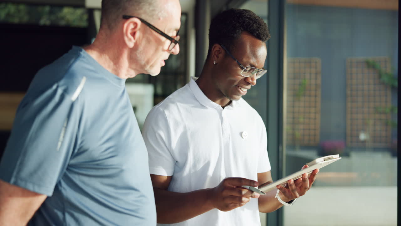 Two Diverse Men Discussing Information on a Digital Tablet