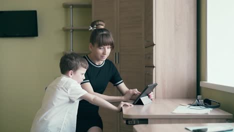 mother-helps-her-son-do-homework-for-school-uses-a-tablet-computer