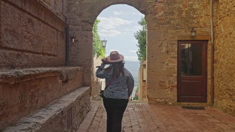 touristin geht in richtung bogen in pienza, toskana, italien