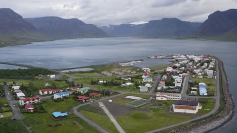 aerial panoramic shot of flateyri village in westfjords of iceland during cloudy day - mountain range in background