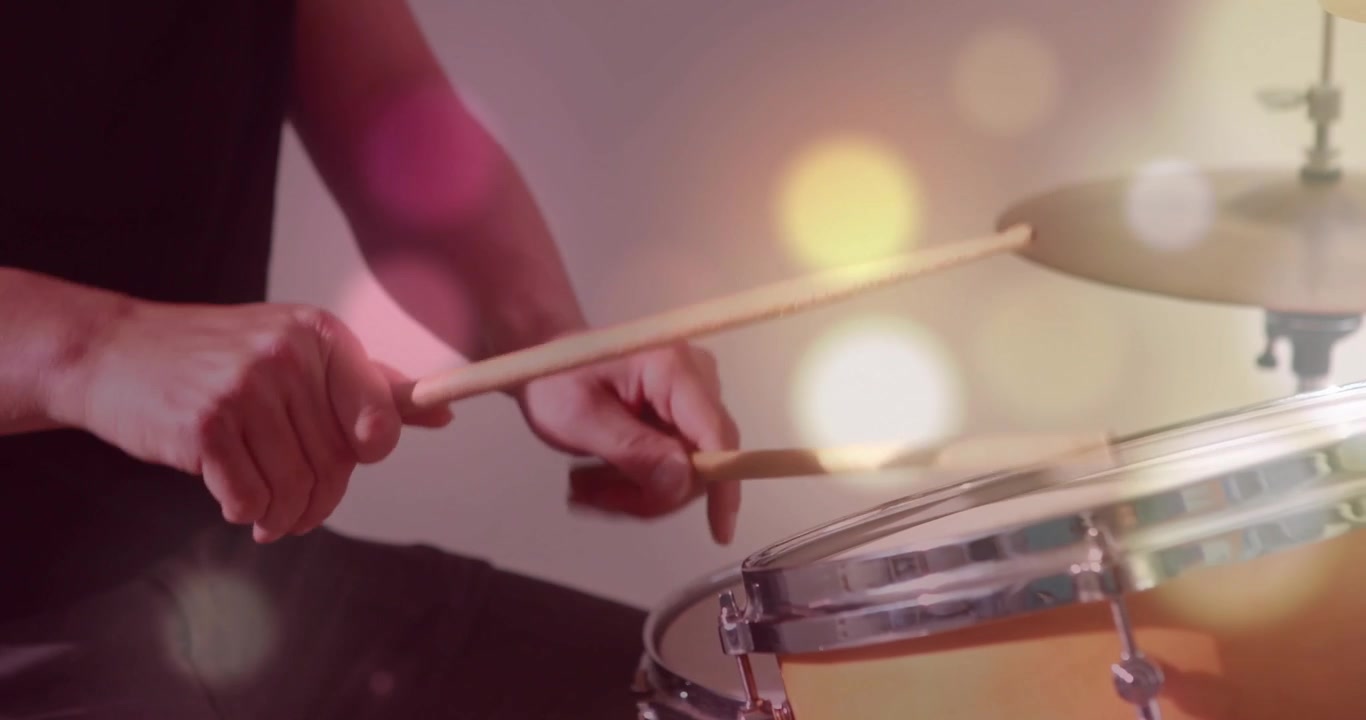 Drummer tapping snare and cymbal with sticks in music studio, first tap starting bokeh peaking beat
