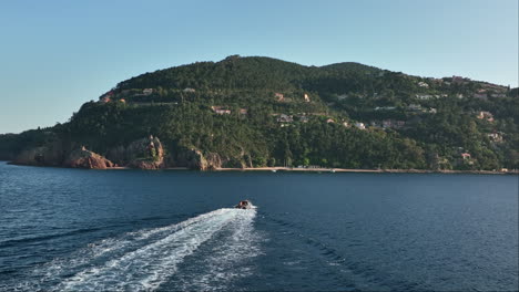 el barco se desliza por la punta de l'aiguille; el telón de fondo de théoule-sur-mer.