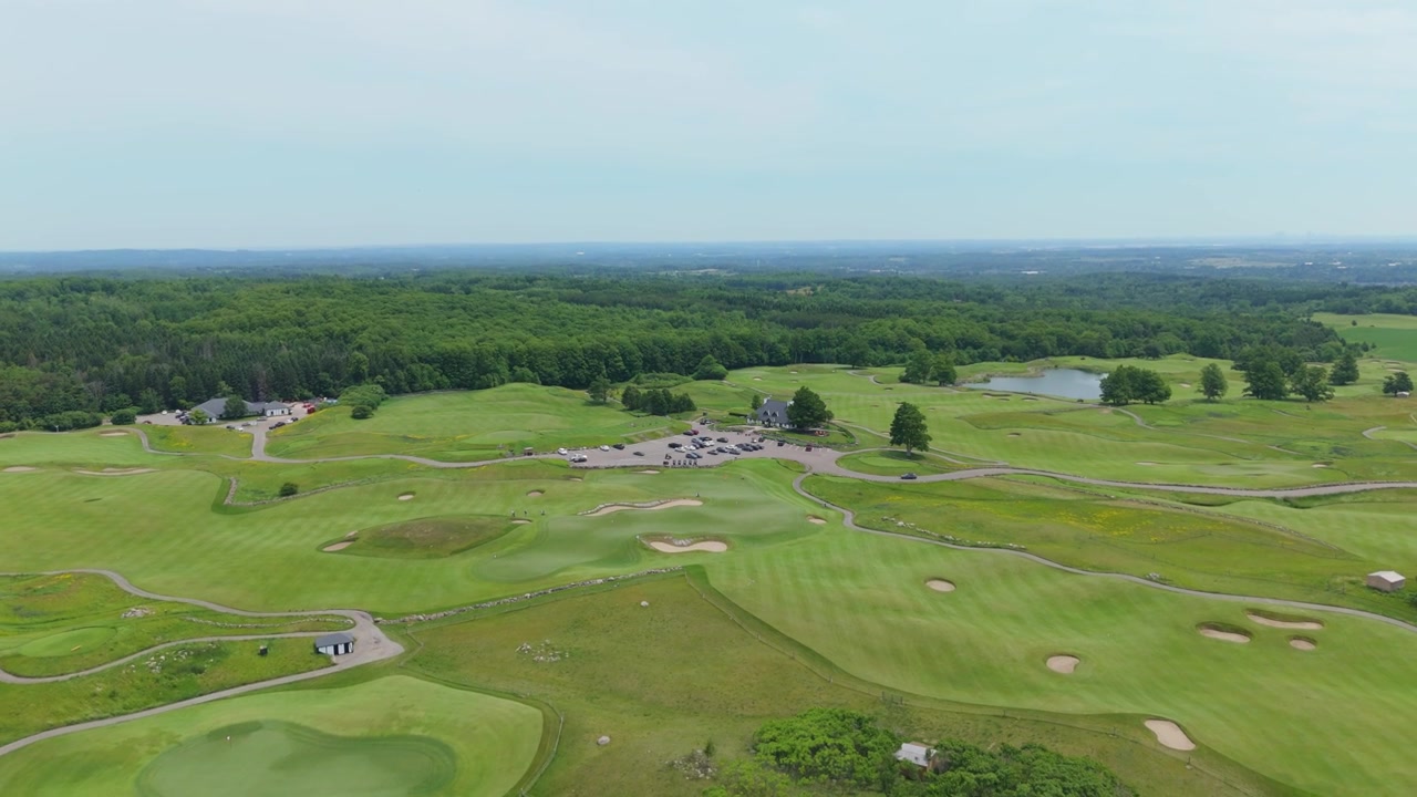 Central parking area and surrounding greens of The Paintbrush course seen from a high drone flyover.