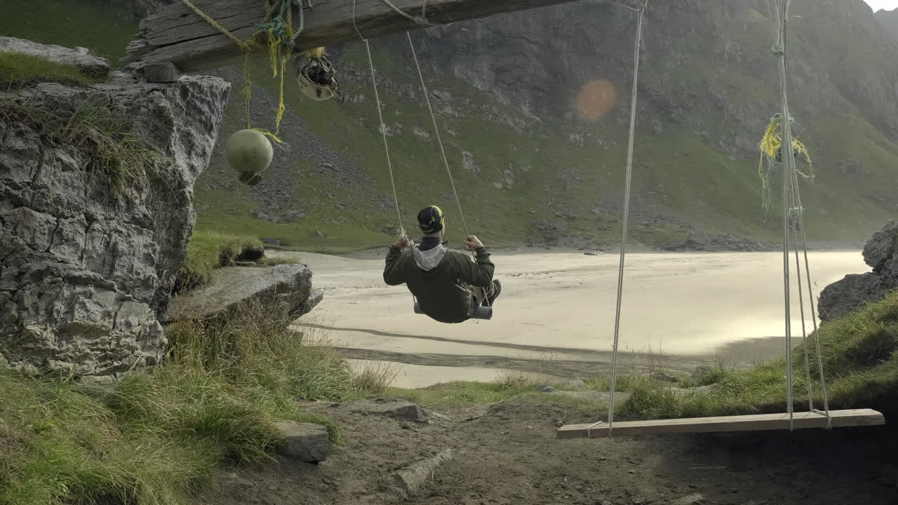 크발비카 해변에서 그네를 타며 노르웨이 로포텐의 전망을 즐기는 남자