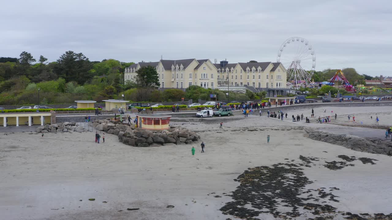 사람들은 salthill promenade를 따라 걸어서 ladies beach galway에서 아름다운 아일랜드 하루를 즐기고 있습니다.