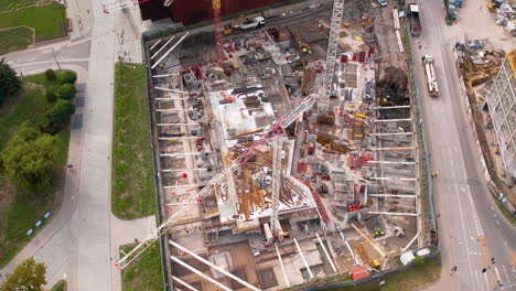 drone descends on construction site with scaffolding and large crane from construction workers