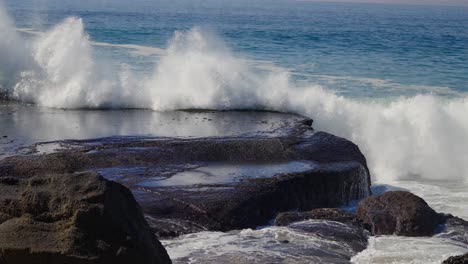 ola del océano explotando en las rocas y lavando