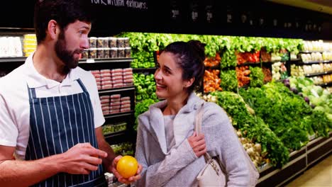 smiling male staff assisting a woman with grocery shopping