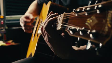 joven músico comprobando las cuerdas de una guitarra acústica de cerca. guitarrista masculino afinando el sonido de un instrumento musical.