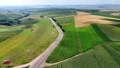 Farmland and highway vista. Expansive fields stretch across the landscape, with a winding highway connecting small towns in the distance
